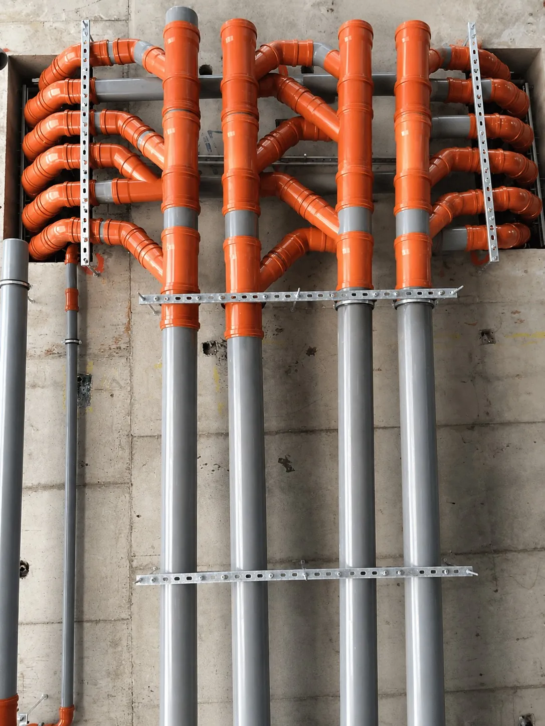 Drainage stacks and vertical service risers bracketed to a concrete wall